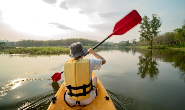 Mujer asiática en kayak en el lago sola. Campamento de verano y actividad al aire libre en solitario