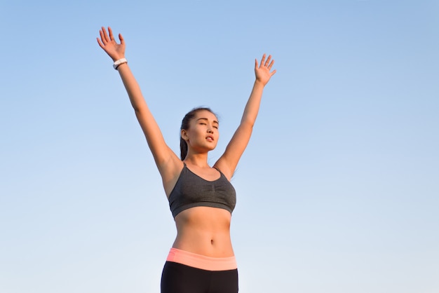 Mujer asiática levantando los brazos al cielo.