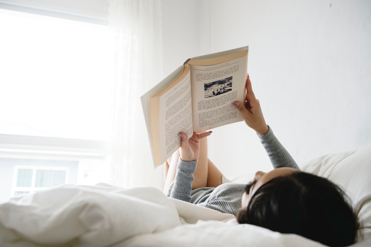 Foto una mujer asiática leyendo en una cama en una habitación mínima luminosa