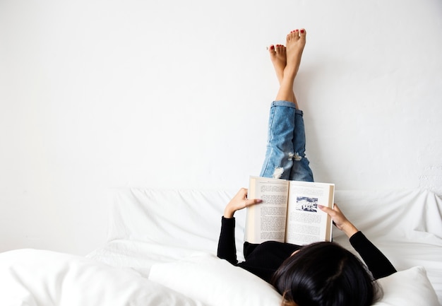 Una mujer asiática leyendo un libro en casa