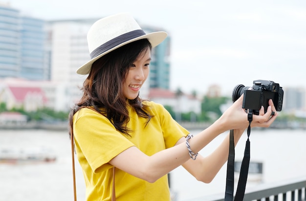 Mujer asiática linda joven en el estilo casual que hace el selfie con la cámara en la ciudad urbana al aire libre