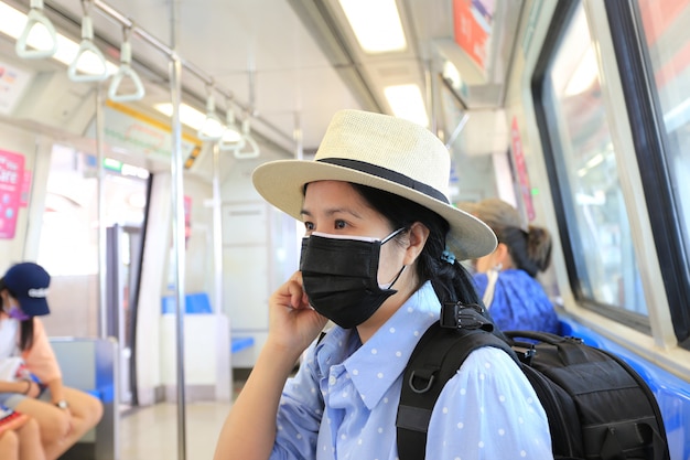 Mujer asiática con máscara de carbono para proteger el smog o PM 2.5 y virus en el tren del metro