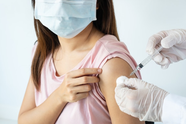 Mujer asiática en máscara médica recibiendo covid-19 o vacuna contra la gripe en el hospital