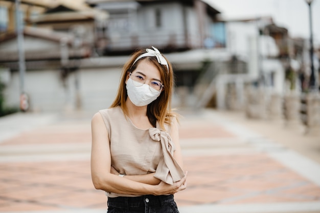 Mujer asiática con mascarilla blanca para proteger el virus de la corona, mascarilla de protección antivirus con estándar para prevenir el coronavirus COVID-19