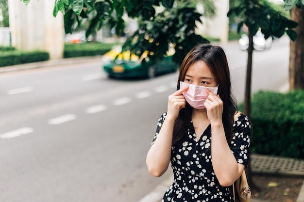 Mujer asiática con mascarilla para protegerse del brote de Coronavirus COVID19 en la ciudad