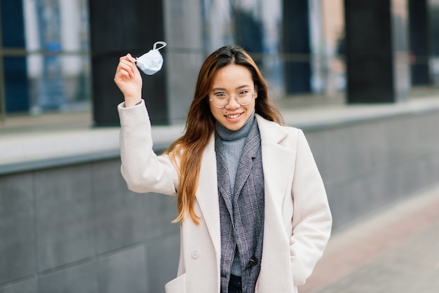 Mujer asiática con mascarilla quirúrgica, protección facial en la ciudad, café