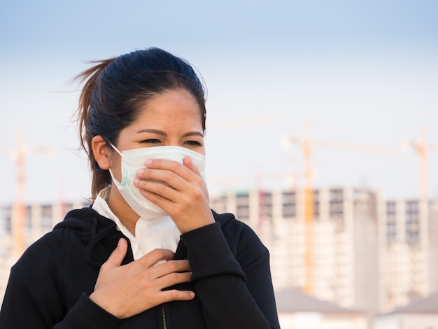 Mujer asiática con mascarilla y tos por contaminación
