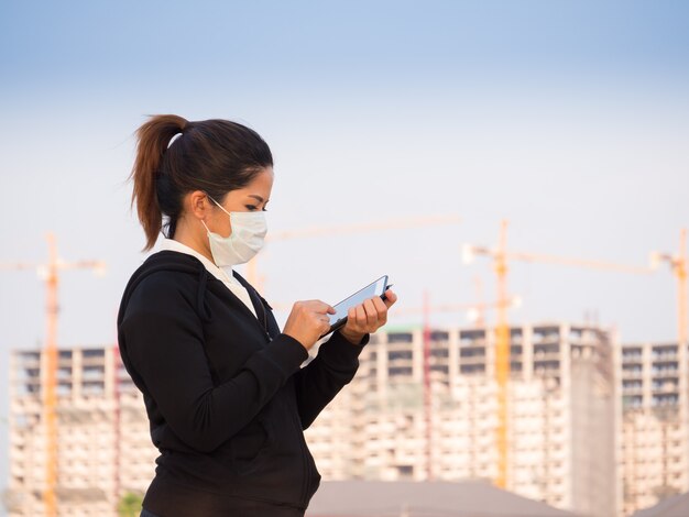 Mujer asiática con mascarilla y trabajando con antecedentes de construcción