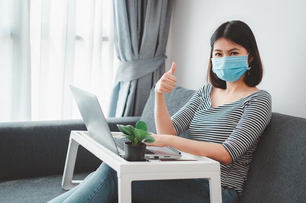 Mujer asiática con mascarilla trabajando en casa