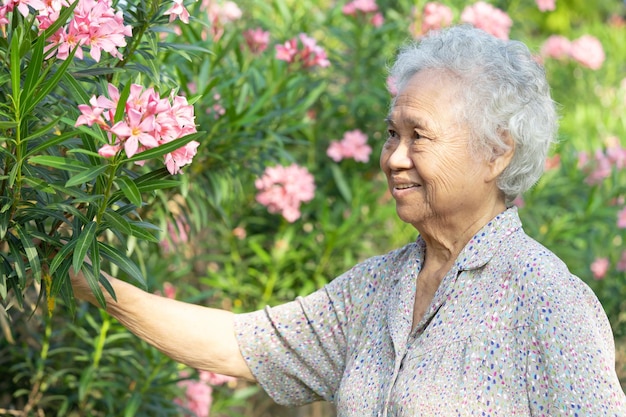 Mujer asiática mayor o anciana camina para hacer ejercicio con flores en el parque