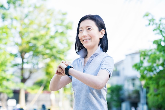 Foto mujer asiática de mediana edad operando un reloj inteligente al aire libre