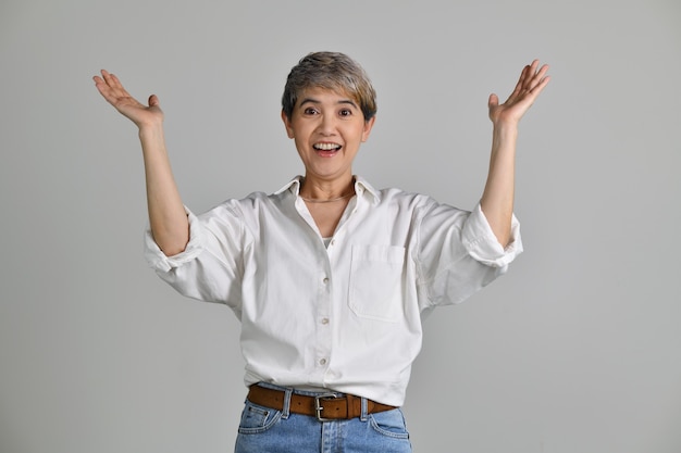 Mujer asiática de mediana edad sorprendida gritando sobre fondo blanco. Mirando a la camara