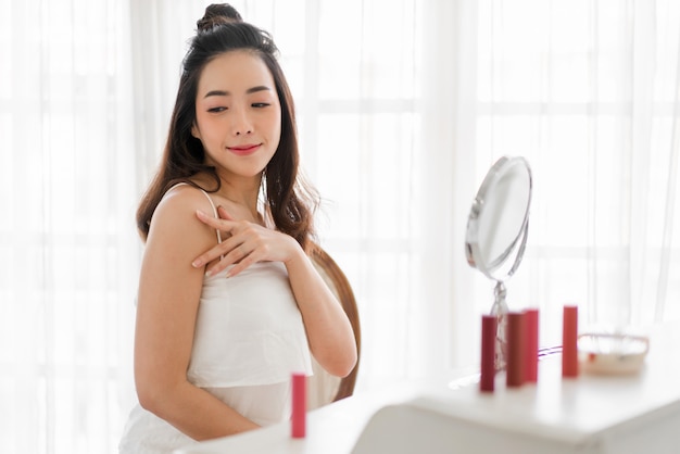 mujer asiática, mirar espejo, aplicación, crema, en casa