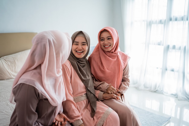 Mujer asiática muslimah disfruta chateando mientras está sentado en la cama