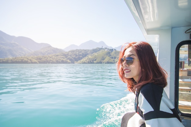 Una mujer asiática navega en un yate en el mar, mirando hacia la distancia. día soleado