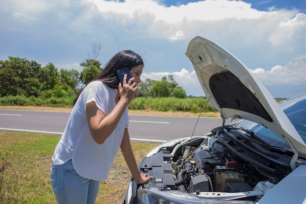 Mujer asiática necesita ayuda con un coche roto con capota abierta