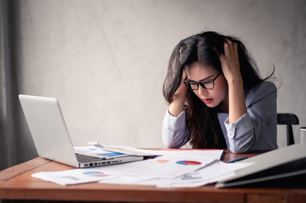 Mujer asiática de negocios estresada usando laptop y trabajando