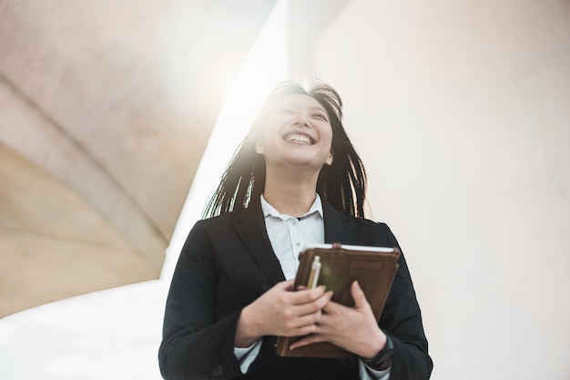 Mujer asiática de negocios que va a trabajar - Feliz mujer empresaria fuera de la oficina después de una startup - Tecnología, empresario y concepto de trabajo - Centrarse en su rostro