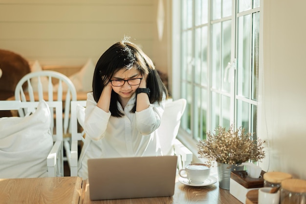 La mujer asiática de negocios se siente cansada y mantiene la cabeza seria y trabaja con una computadora portátil