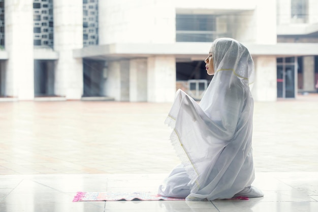 Mujer asiática orando por Alá en la mezquita