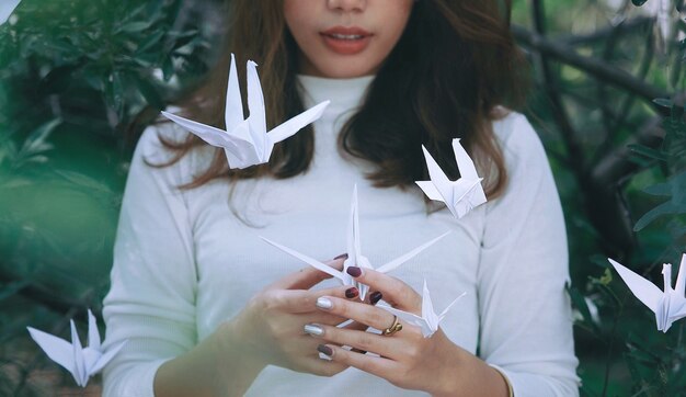 Foto mujer asiática con pájaro de origami en el jardín