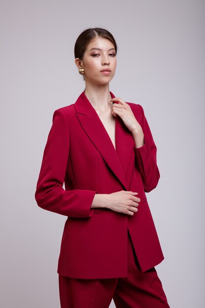 Mujer asiática en pantalones de chaqueta de traje rojo posando sobre fondo gris suave blanco Foto de estudio