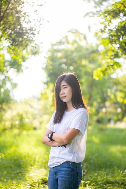 Mujer asiática con pelo largo en camisa blanca sobre fondo natural