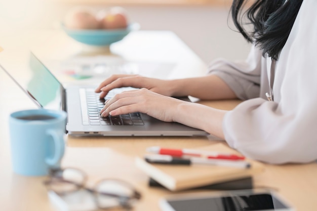 Mujer asiática de pelo negro trabajando desde casa usando una computadora portátil