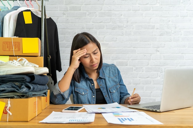 Mujer asiática pensando mucho en vender en línea start-up pequeña empresa owne