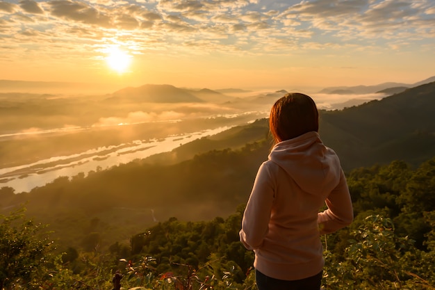 Mujer asiática de pie, mirando el amanecer y el mar de niebla en el río Mekong, Tailandia