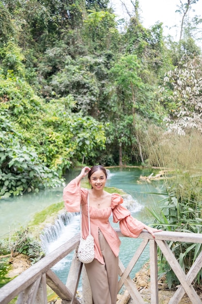 Mujer asiática de pie en la pasarela de madera en la cascada de Kuang Si Lung Prabang Laos