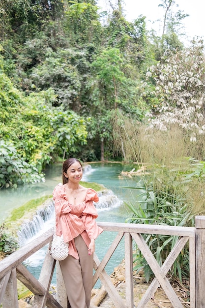 Mujer asiática de pie en la pasarela de madera en la cascada de Kuang Si Lung Prabang Laos