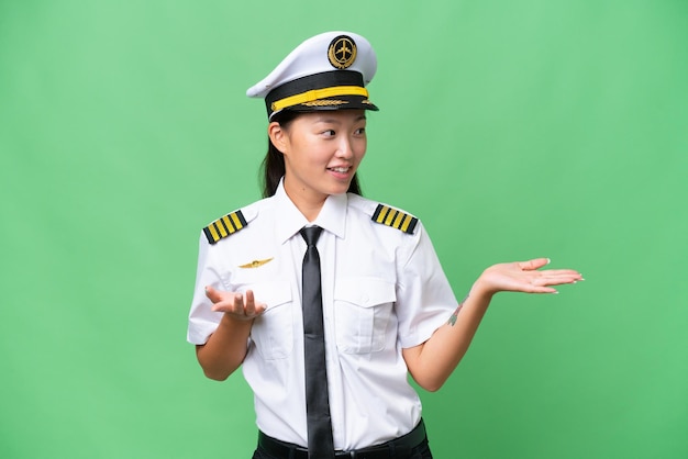 Mujer asiática piloto de avión sobre antecedentes aislados con expresión facial sorpresa