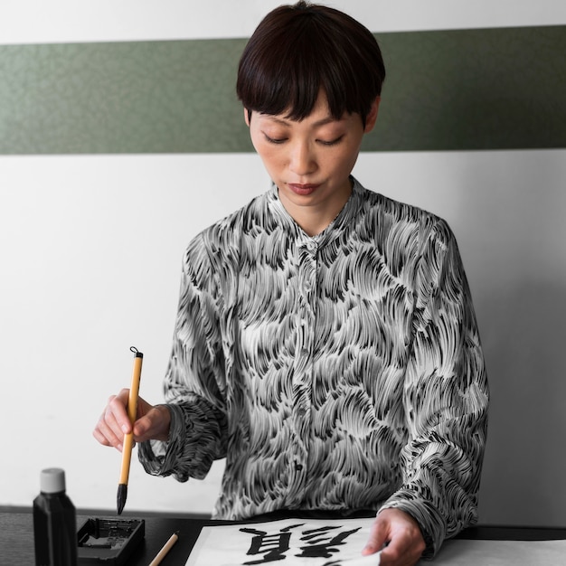 Foto mujer asiática pintando letras japonesas