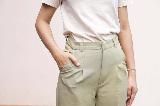 Mujer asiática pone su mano derecha en el bolsillo de sus pantalones