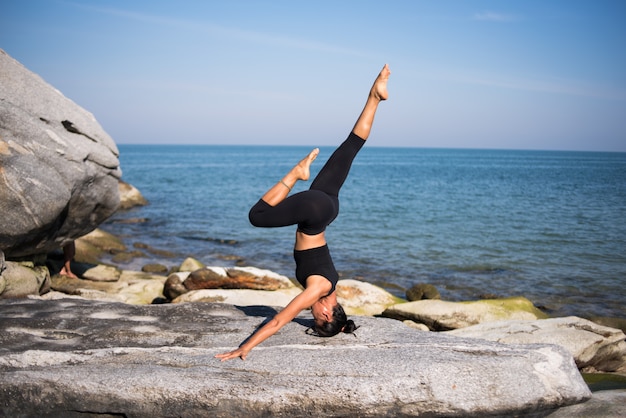 Mujer asiática practica yoga en la playa