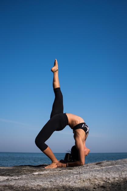 Mujer asiática practica yoga en la playa