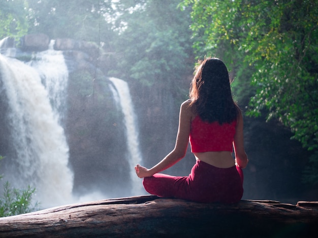 Foto mujer asiática practicando o haciendo yoga en la cascada