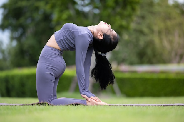 Mujer asiática practicando yoga en el jardín