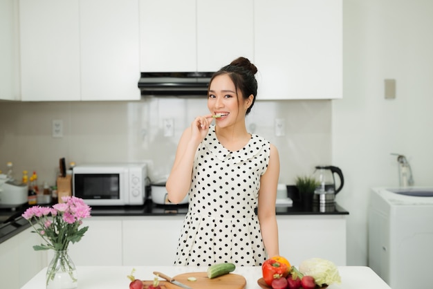 Mujer asiática preparando comida saludable en su cocina rústica ecológica