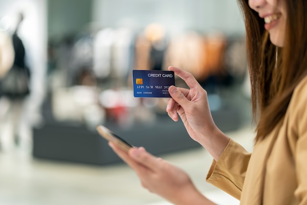 Foto mujer asiática del primer que usa la tarjeta de crédito con el móvil para las compras en línea en grandes almacenes