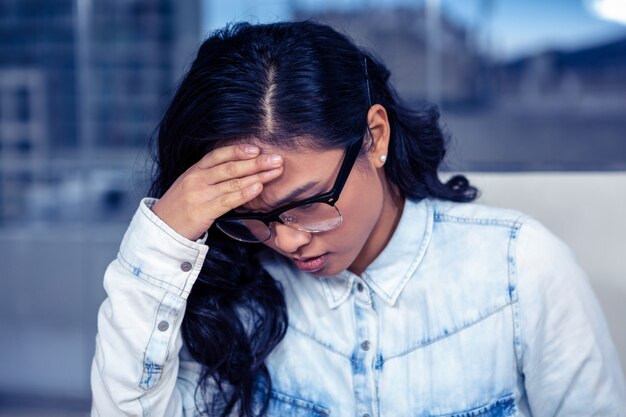 Mujer asiática con problemas con la mano en la cara en la oficina