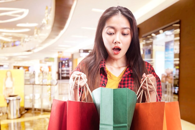 Mujer asiática, proceso de llevar, bolsas de compras, en, el, centro comercial