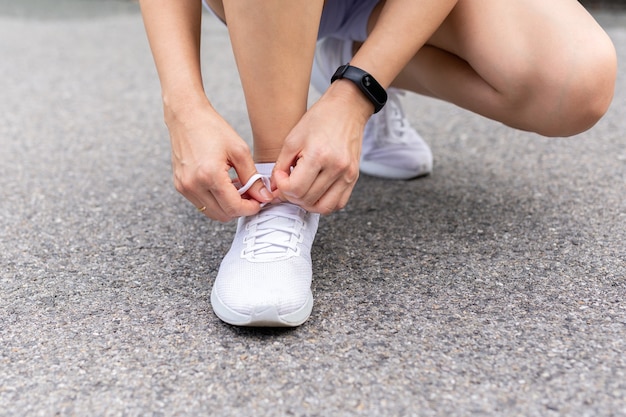 Mujer asiática que ata los cordones que se preparan para correr ejercicio