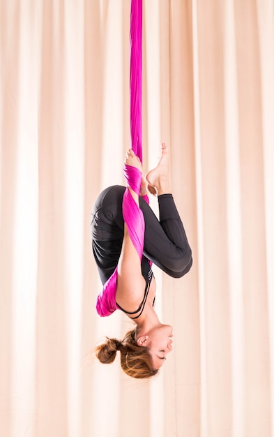 Mujer asiática que entrena en sala de fitness con elementos de yoga mosca