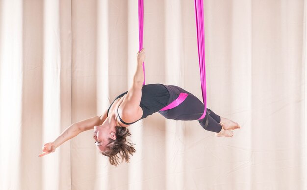 Mujer asiática que entrena en sala de fitness con elementos de yoga mosca