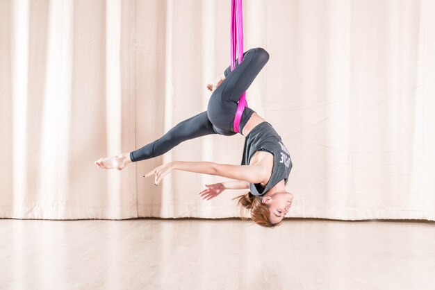 Mujer asiática que entrena en sala de fitness con elementos de yoga mosca