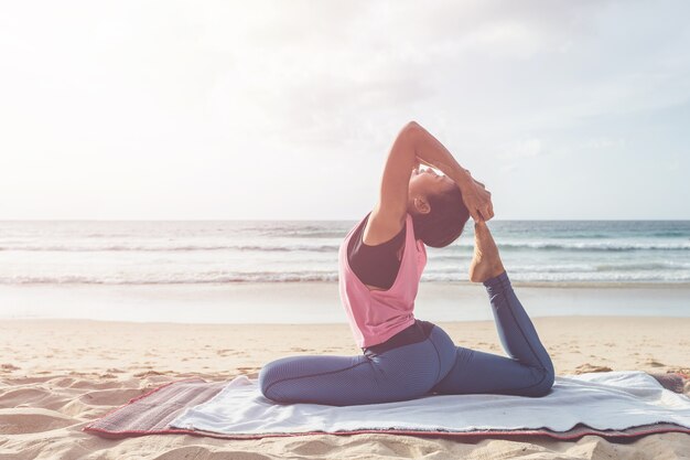 Mujer asiática que juega yoga y ejercicio en la playa tropical en Tailandia