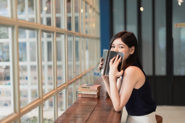 Mujer asiática que lee un libro en el coffeeshop.