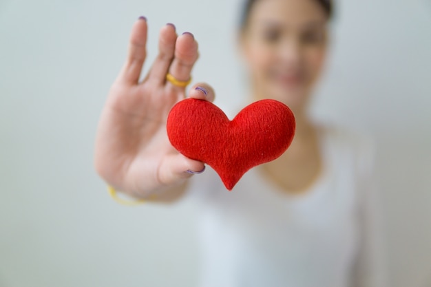 Mujer asiática que lleva a cabo un corazón rojo en sus manos.